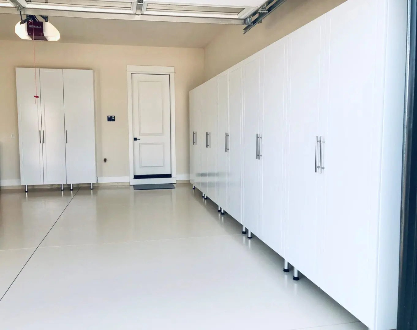 A white garage with many cabinets and doors.