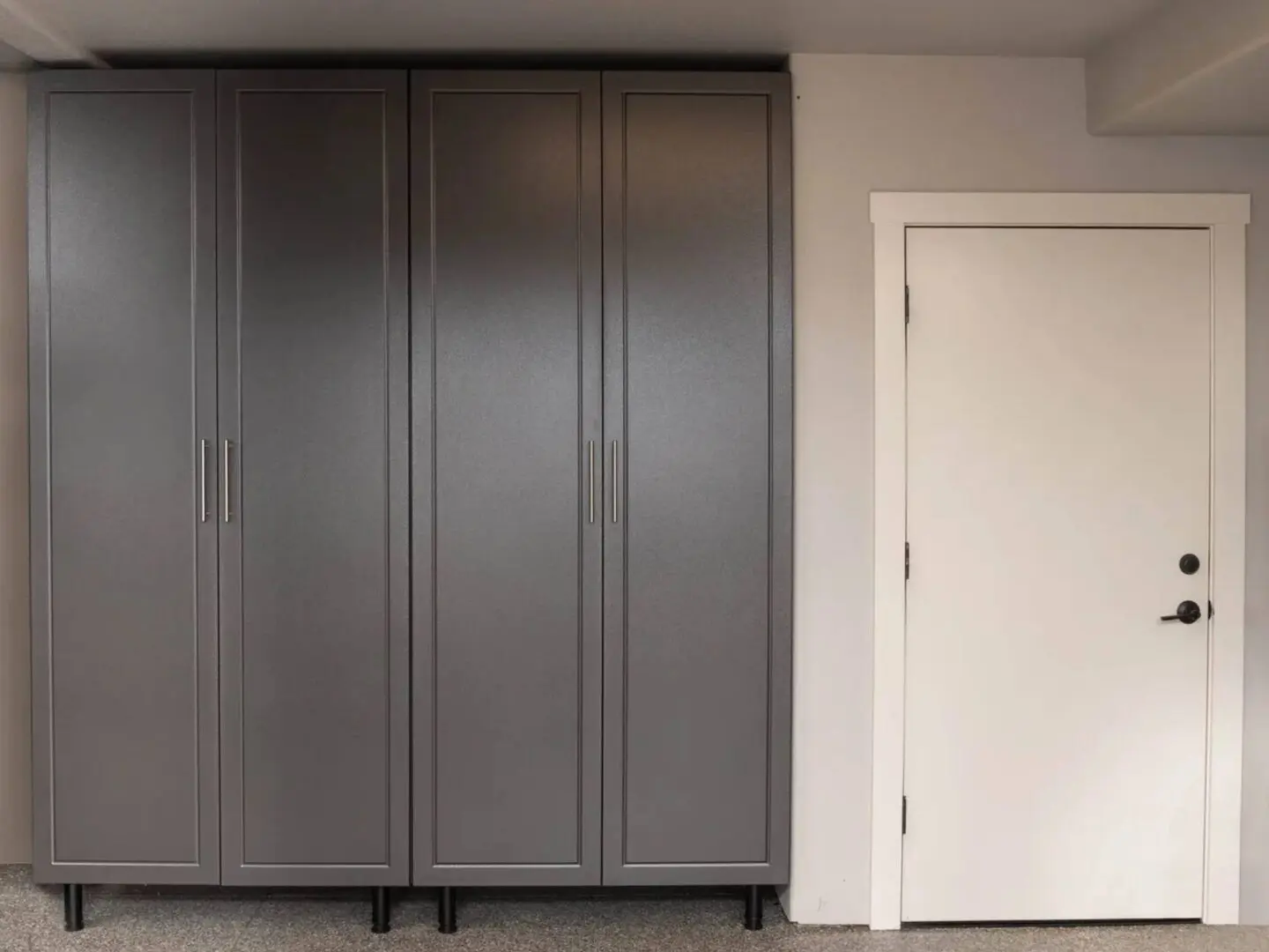 A room with three gray cabinets and a door.